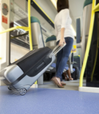 Rail floors header. A lady with a suitcase walks into the carriage of a train.