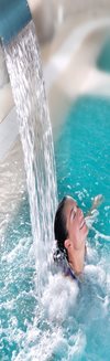 Link to Leisure. A woman smiles whilst standing under a cascade of water in a swimming pool.