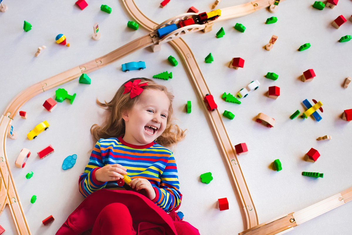 Image of a child laying on Altro Serenade surrounded by a toy railway