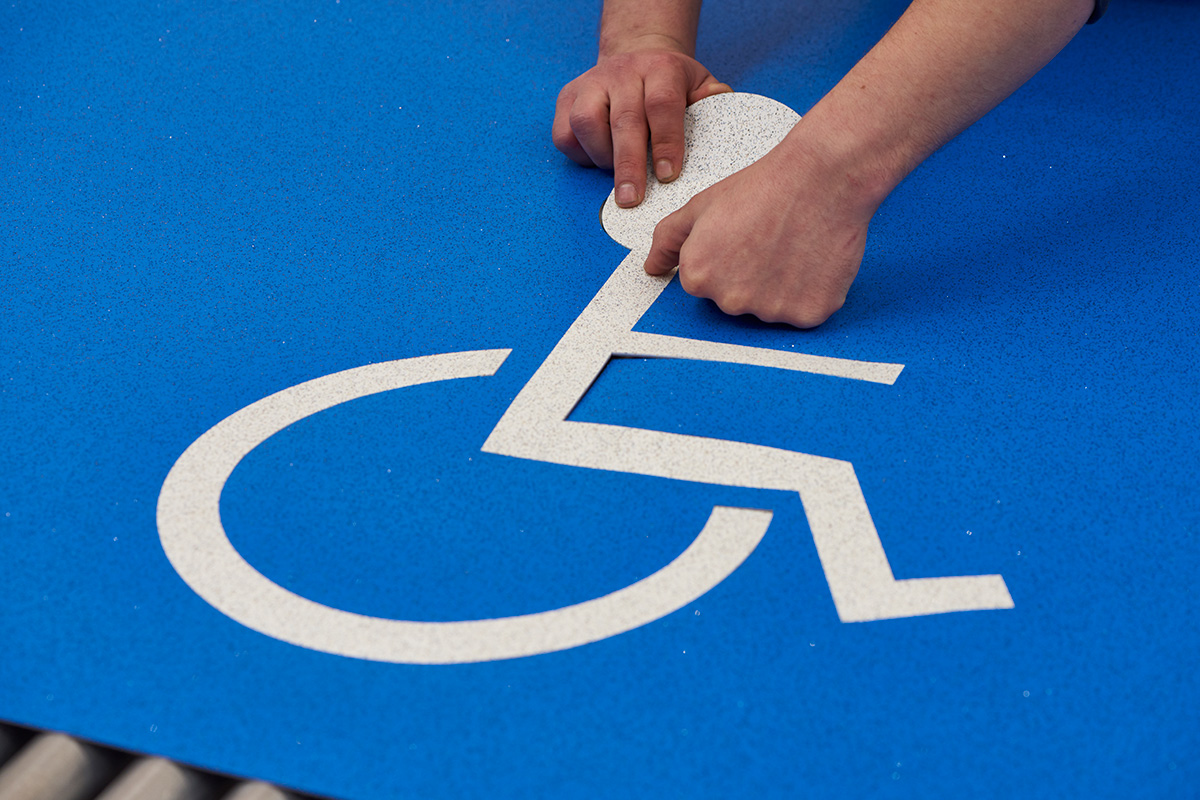 photograph of precision-cut wheelchair logo being inlaid in Altro safety flooring